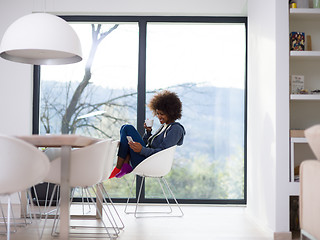 Image showing black woman drinking coffee and using a mobile phone  at home