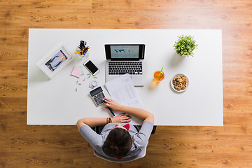 Image showing woman with calculator and papers at office table