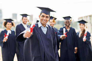 Image showing happy students in mortar boards with diplomas