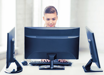 Image showing businesswoman with computer and monitors in office