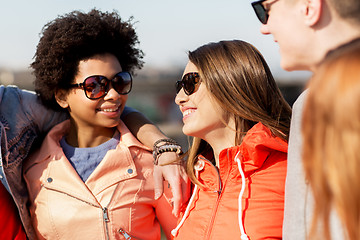 Image showing happy teenage friends in shades talking on street