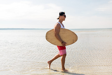 Image showing happy young man with skimboard on summer beach