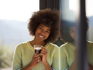 Image showing African American woman drinking coffee looking out the window