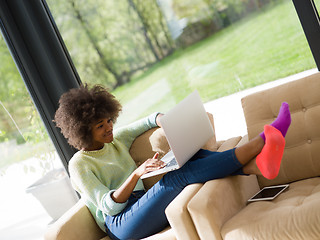 Image showing African American woman using laptop on sofa