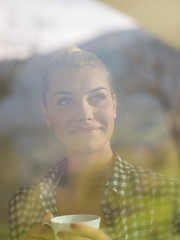 Image showing young woman drinking morning coffee by the window