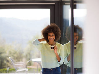 Image showing African American woman drinking coffee looking out the window