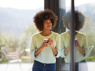 Image showing African American woman drinking coffee looking out the window