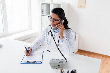 Image showing doctor with clipboard calling on phone at hospital