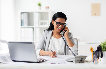 Image showing happy businesswoman calling on phone at office