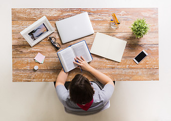 Image showing woman reading book at wooden table