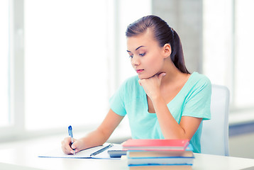 Image showing tired student writing in notebook