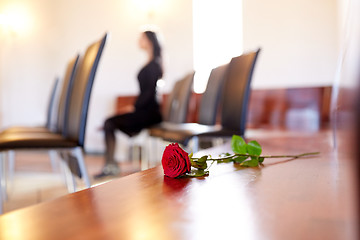 Image showing red roses and woman crying at funeral in church