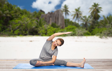 Image showing happy woman doing yoga and stretching on beach