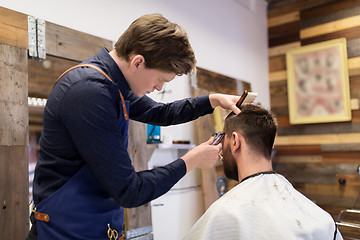 Image showing man and barber with trimmer cutting hair at salon