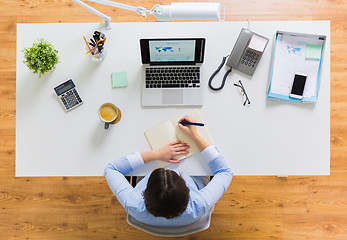 Image showing businesswoman writing to notebook at office