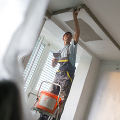 Image showing Plasterer renovating indoor walls and ceilings. Construction finishing works.