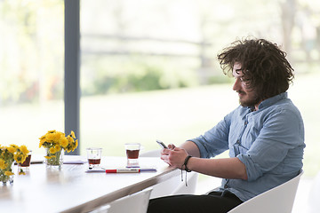 Image showing young man using a mobile phone  at home