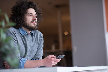 Image showing Young casual businessman holding smartphone