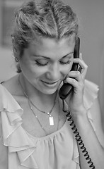 Image showing Smiling girl talking on wire telephone