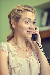 Image showing Smiling girl talking on wire telephone