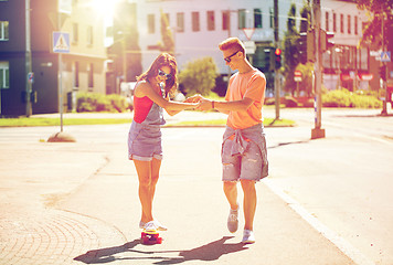 Image showing teenage couple riding skateboards on city street