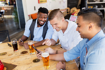 Image showing male friends with smartphone drinking beer at bar