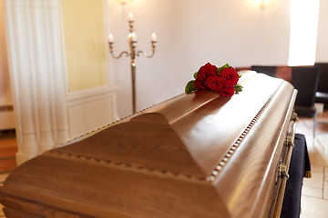 Image showing red rose flowers on wooden coffin in church