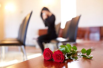 Image showing red roses and woman crying at funeral in church