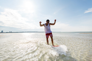 Image showing young man riding on skimboard on summer beach