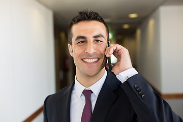 Image showing smiling businessman calling on smartphone at hotel