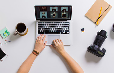 Image showing woman hands with camera working on laptop at table