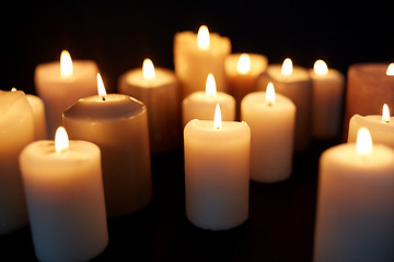 Image showing candles burning in darkness over black background