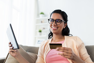 Image showing happy woman with tablet pc and credit card at home