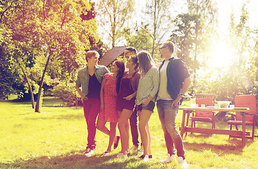 Image showing happy teenage friends talking at summer garden