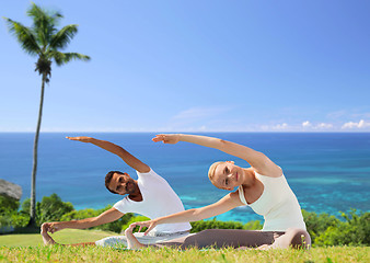 Image showing happy couple making yoga exercises outdoors