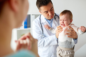 Image showing doctor or pediatrician with crying baby at clinic