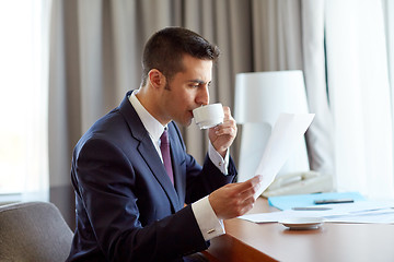 Image showing businessman with papers drinking coffee at hotel