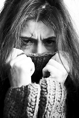 Image showing young brunette gloomy woman in sweater all over her face, messed hair