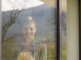 Image showing young woman drinking morning coffee by the window