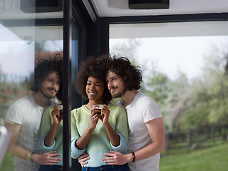 Image showing happy multiethnic couple relaxing at modern home indoors