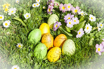 Image showing colored Easter eggs hidden in flowers and grass