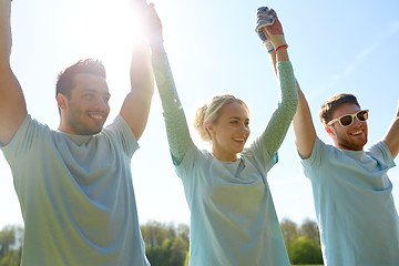 Image showing group of happy volunteers holding hands outdoors