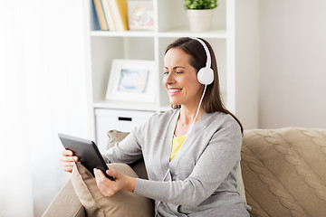 Image showing happy woman with tablet pc and headphones at home