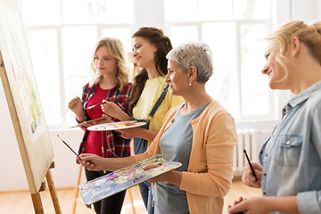 Image showing women with easel and palettes at art school