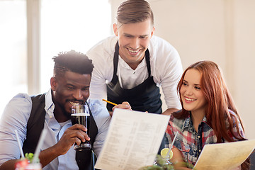 Image showing waiter and couple with menu and drinks at bar