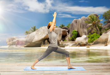 Image showing happy woman doing yoga warrior pose on beach