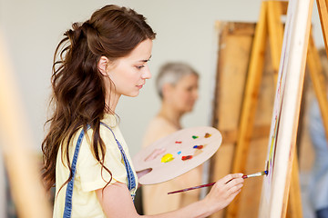 Image showing student girl with easel painting at art school