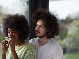 Image showing happy multiethnic couple relaxing at modern home indoors