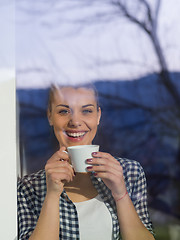 Image showing young woman drinking morning coffee by the window