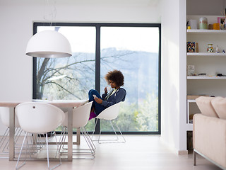 Image showing black woman drinking coffee and using a mobile phone  at home